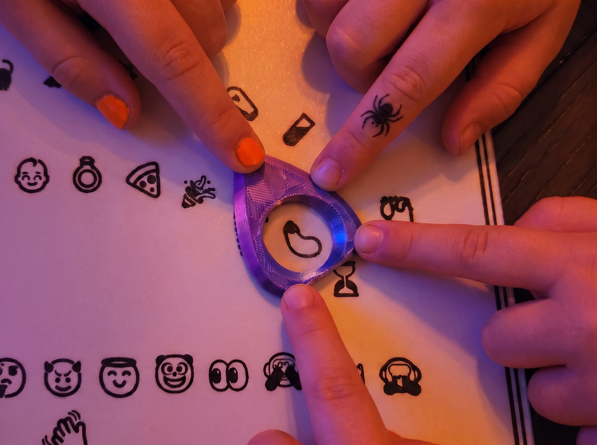 Fingertips resting on the planchette over the eggplant emoji