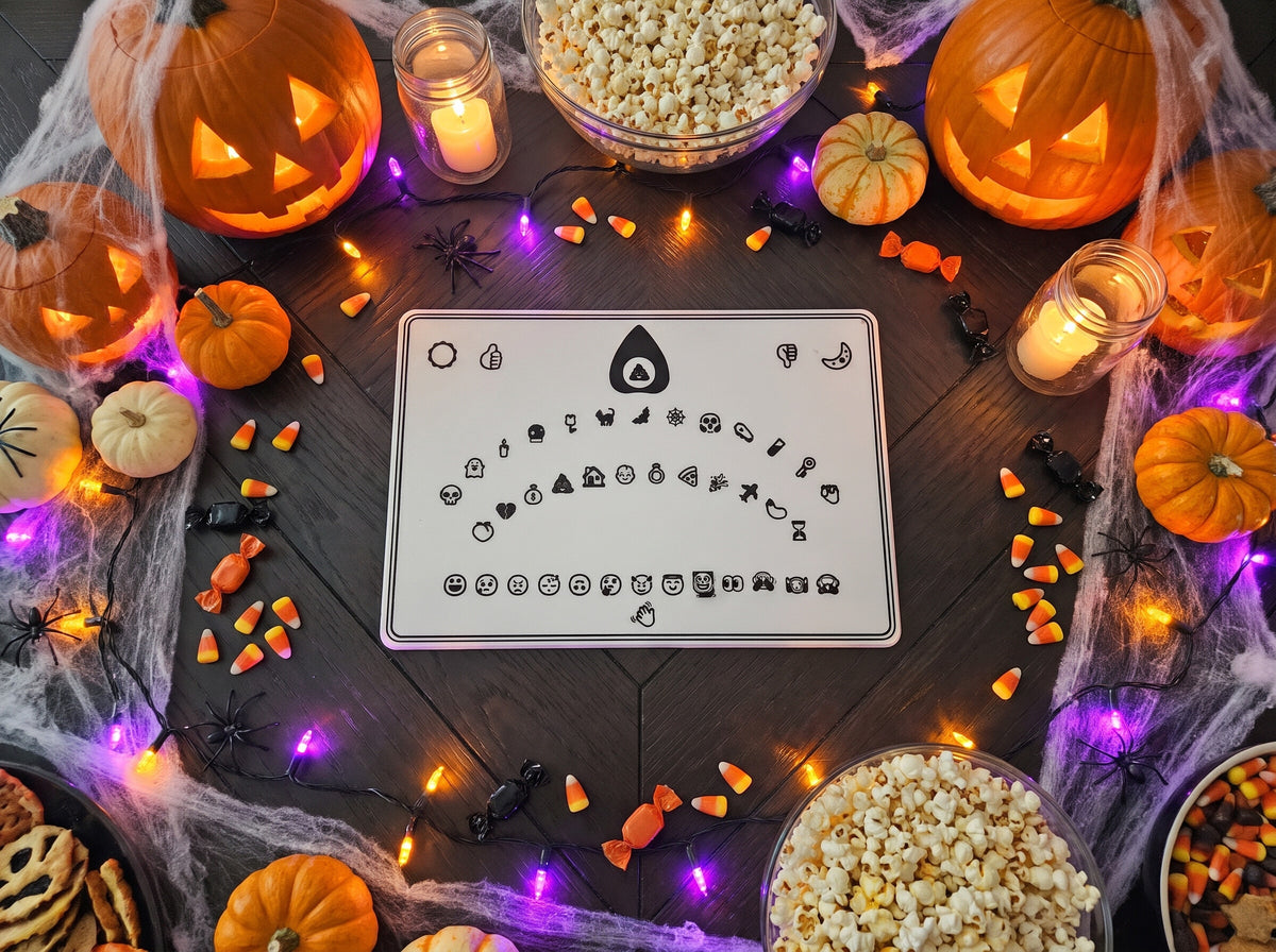 The emoji spirit board from above on a Halloween party table with jack-o-lanterns and string lights