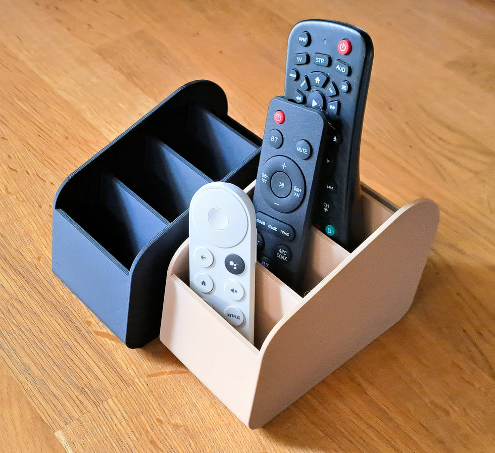 A 3D-printed remote control organizer holding several TV remotes upright
