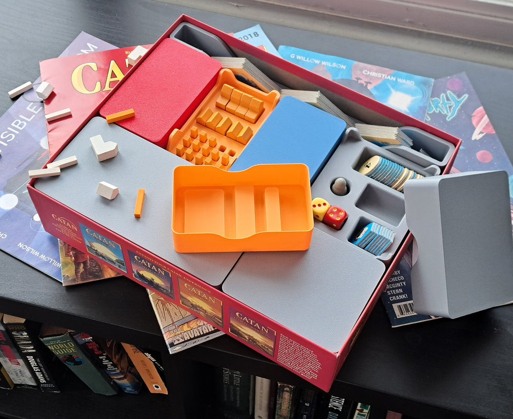 A 3D-printed insert tray organizing the pieces of a hex-tile settlement board game